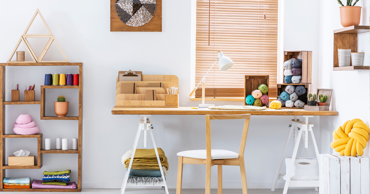 work from home creative business workspace featuring a desk, art supplies, and shelf with more art supplies.