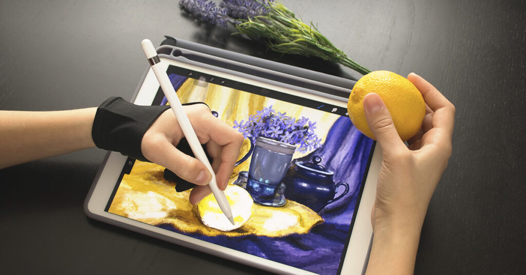 gifts for graphic designers: drawing glove. Image depicts a person using a digital drawing glove drawing a scene on an iPad.