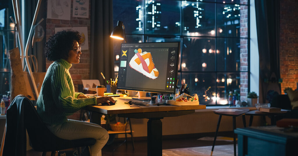 gifts for graphic designers: memberships. Image depicts a woman working in low light on a 3D rendering of a sneaker.