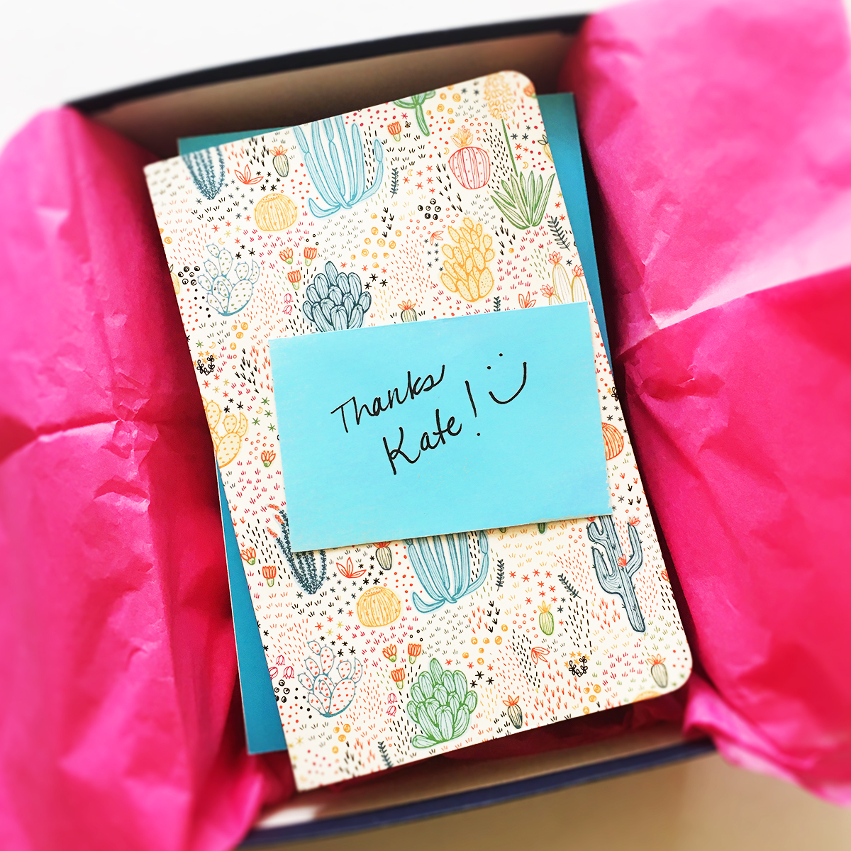 box with hot pink paper filled with cactus print journal and a personal note as a small business human touch.