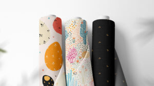 image shows three bolts of fabric - two are brightly colored cactus prints, while one is a black print with gold moons.