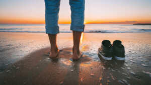 image shows feet and shoes on a beach