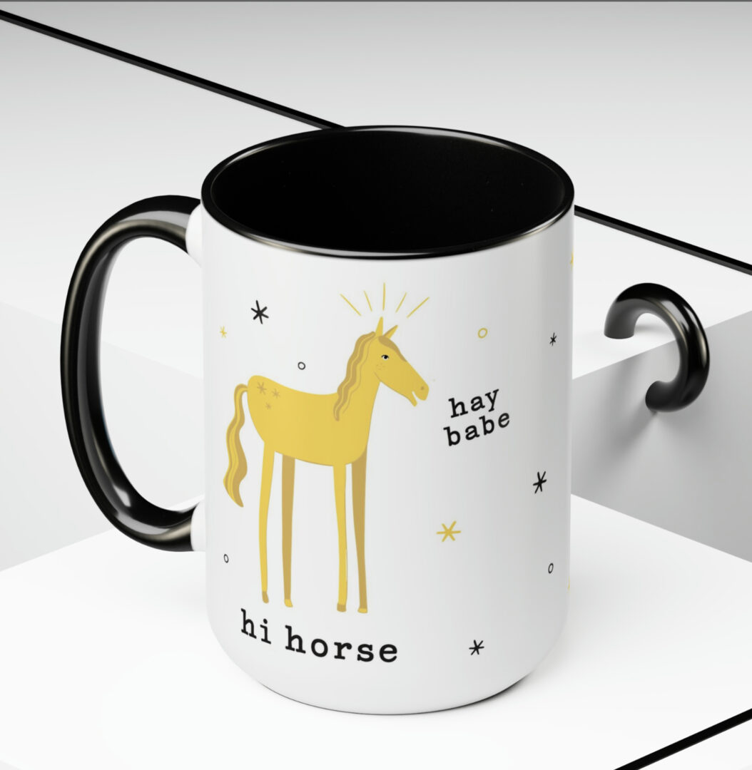 image shows a white mug with a black handle and black inside. The pattern on the mug is gold horse with the words "hay horse" hayyy" and and "hay babe". Creating your own products is easy with print on demand.