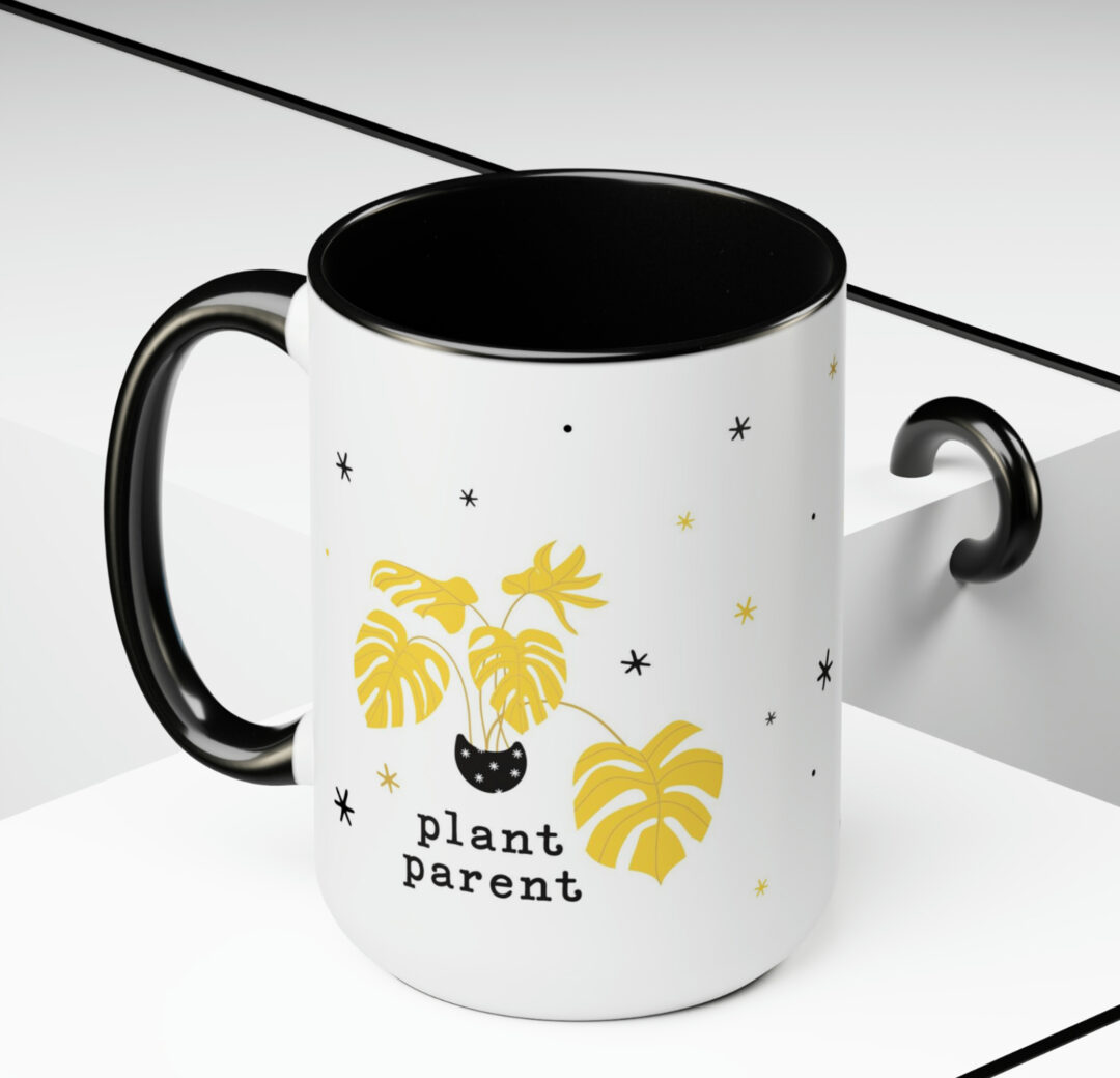 image shows a white mug with a black handle and black inside. The pattern on the mug is gold plant in a black pot with the words "plant parent". Creating your own products is rewarding for every plant parent!